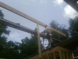 Carpenter setting a ridge beam over a new addition frame — Ice Dam Removal by Roofing Brothers in Medicine Bow