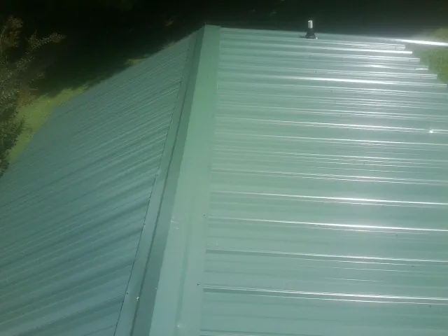 New green metal panels meeting at the ridge of a roof — Flat Roof Repair work by our crew in Medicine Bow