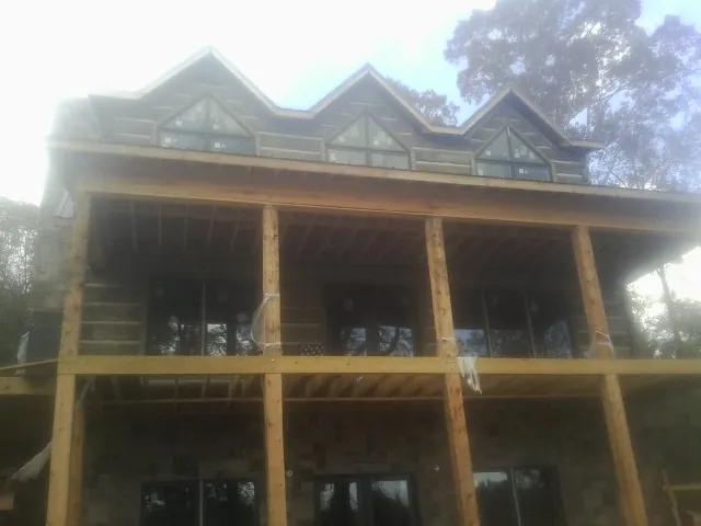 Dormers and porch framing on a large log home under construction — Roof Coating work by our crew in Medicine Bow