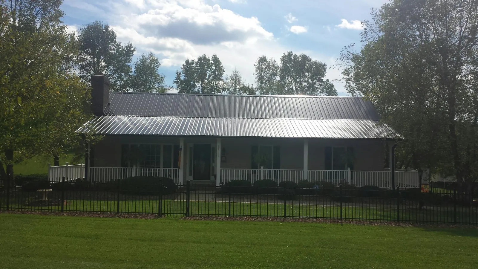 Gray metal roof on a brick ranch with a full width front porch — Gutter Guard Installation work by our crew in Medicine Bow