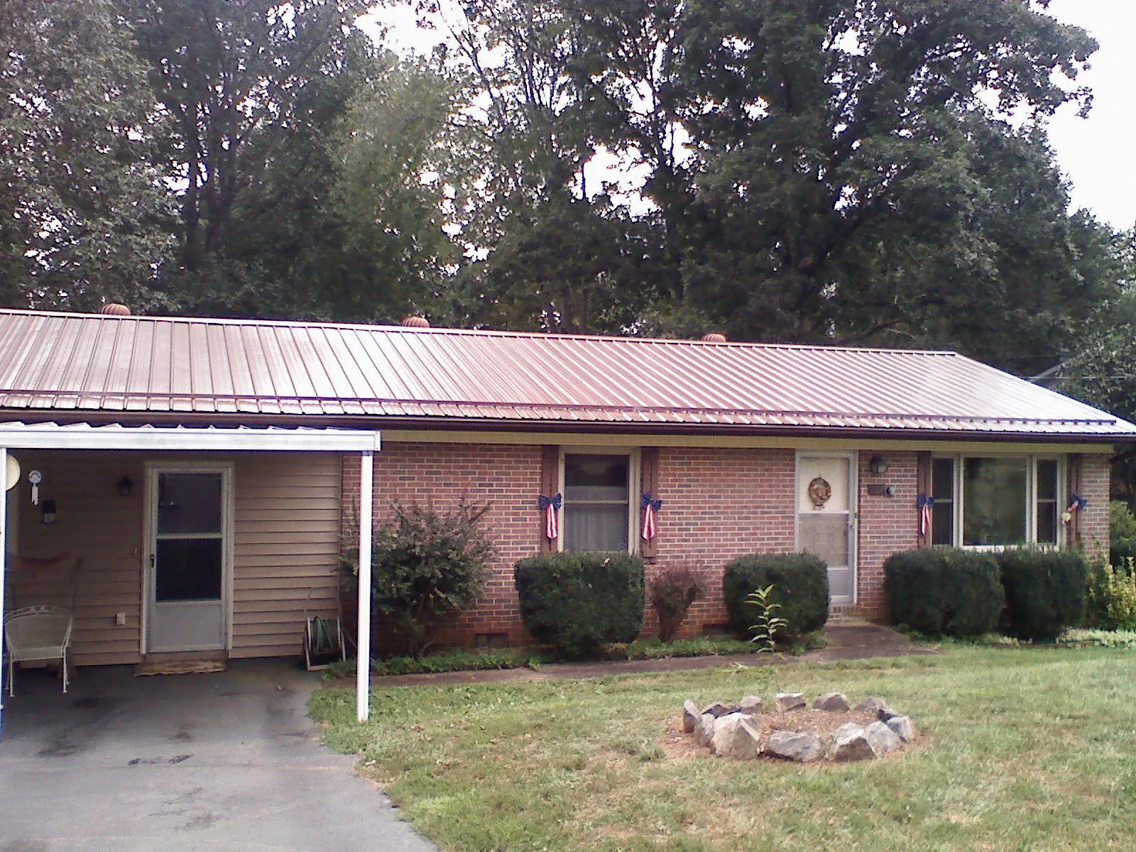 Bronze metal roof and carport on a brick ranch home — Roof Repair work by our crew in Medicine Bow