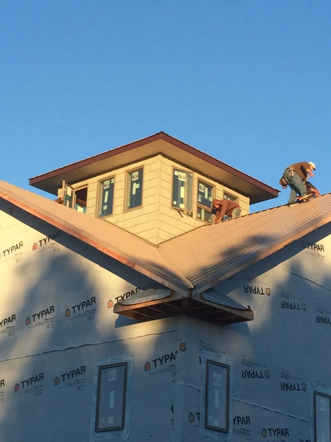 Roofers working around a rooftop cupola on a new metal roof at sunset — Roof Waterproofing in Medicine Bow by Roofing Brothers